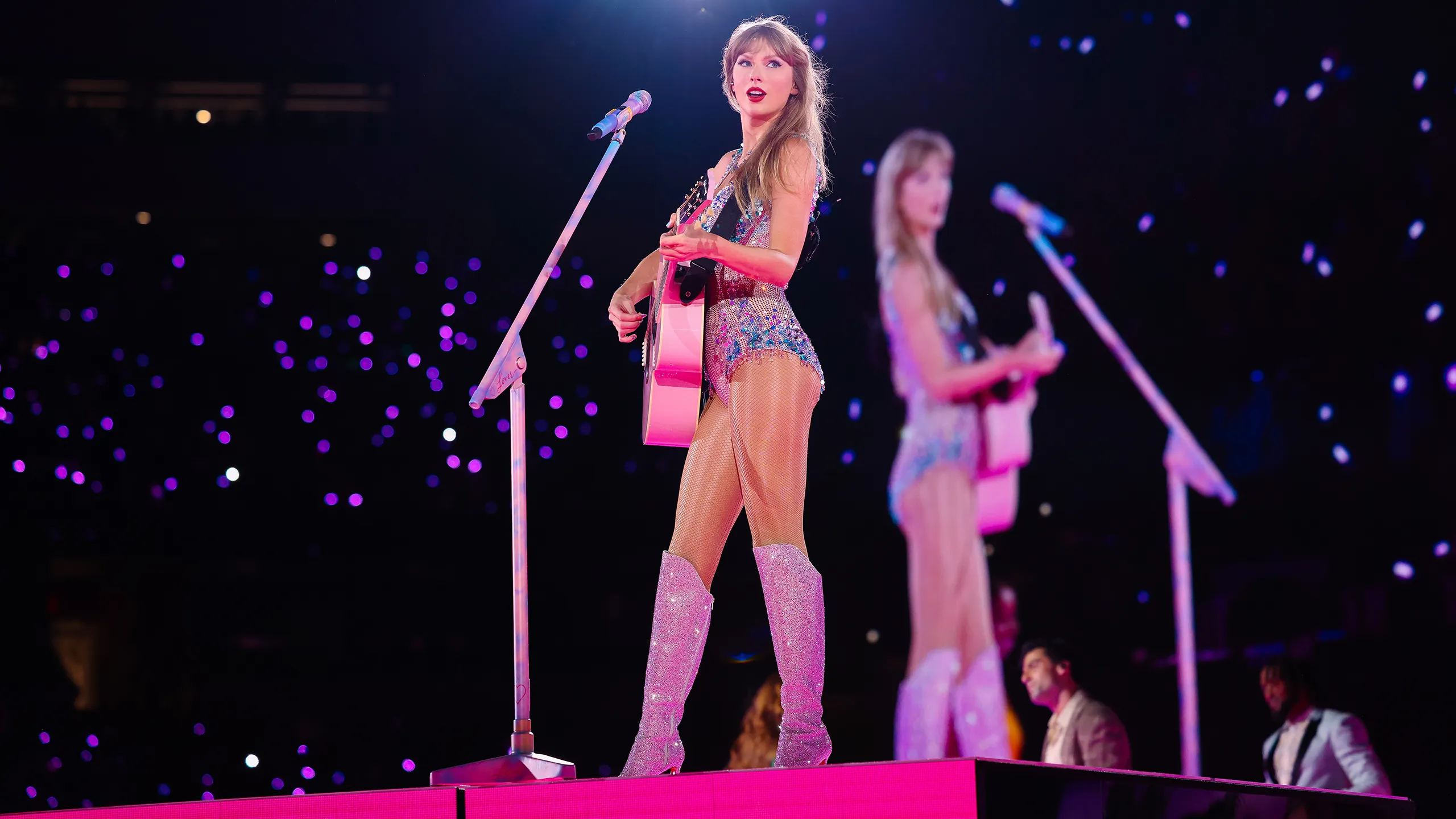Taylor Swift on the Eras Tour stage with a pink acoustic guitar